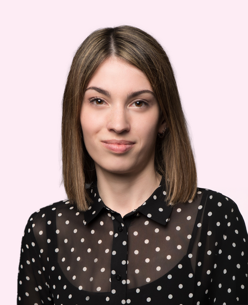 Junge Frau schulterlanges braunes Haar gepunktete schwarze Bluse rosa Hintergrund