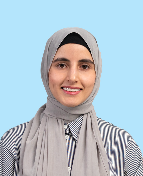 junge Frau mit hellgrauem Hijab und gestreifter Bluse lächelnd vor hellblauem Hintergrund