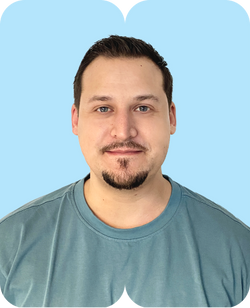 Mann mit kurzem dunklem Haar und Kinnbart im türkisfarbenen T-Shirt vor hellblauem Hintergrund