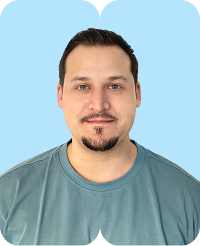 Mann mit kurzem dunklem Haar und Kinnbart im türkisfarbenen T-Shirt vor hellblauem Hintergrund