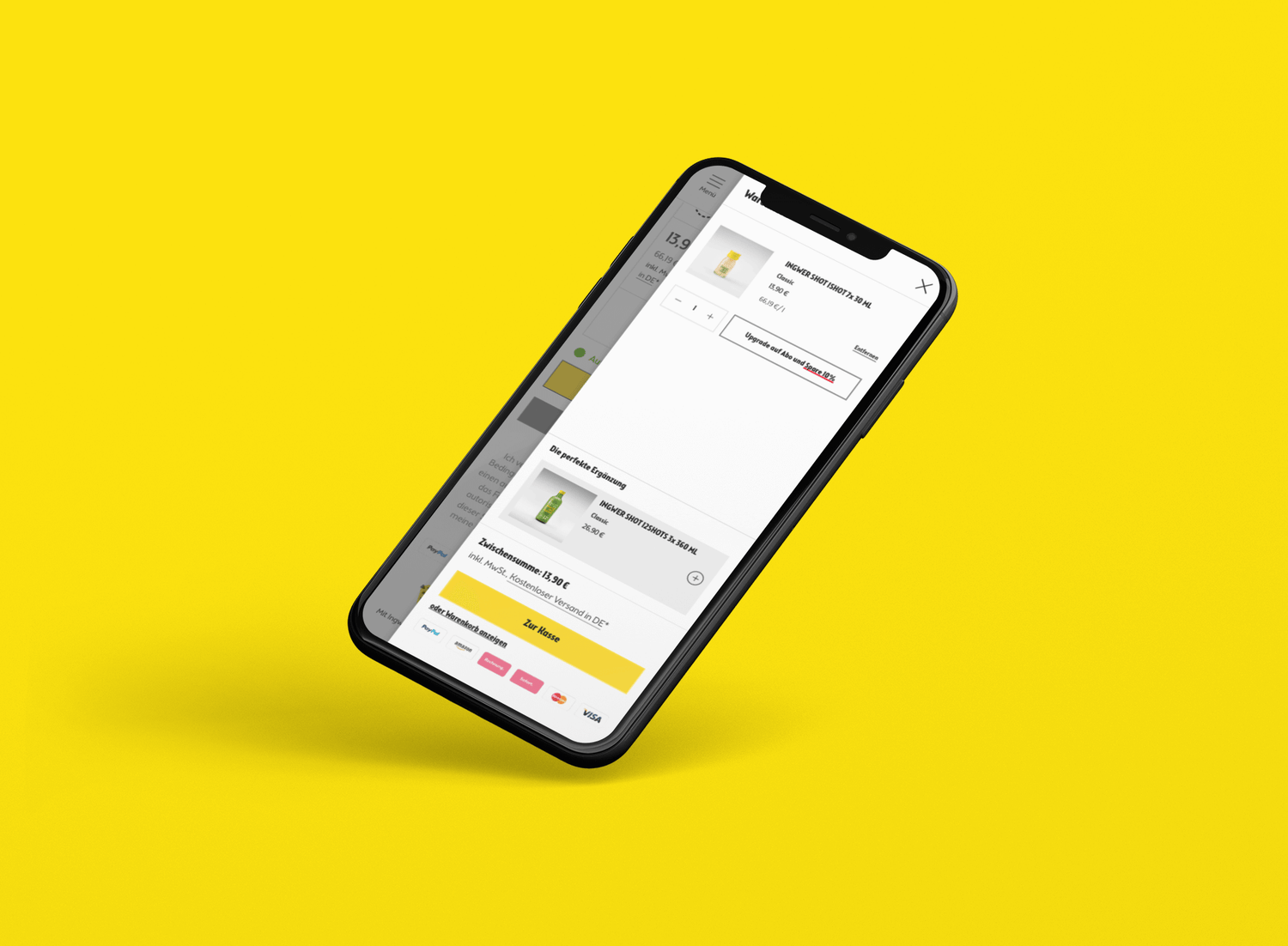schwarzes smartphone vor gelbem hintergrund zeigt webshop-checkout mit ingwer-shot und gelbem bezahlbutton
